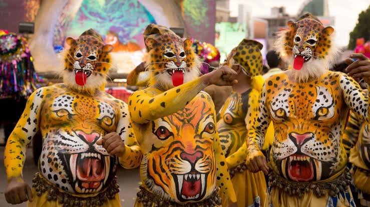 Performers painted as tigers dancing during the traditional Pulikali festival at Swaraj Round, Thrissur